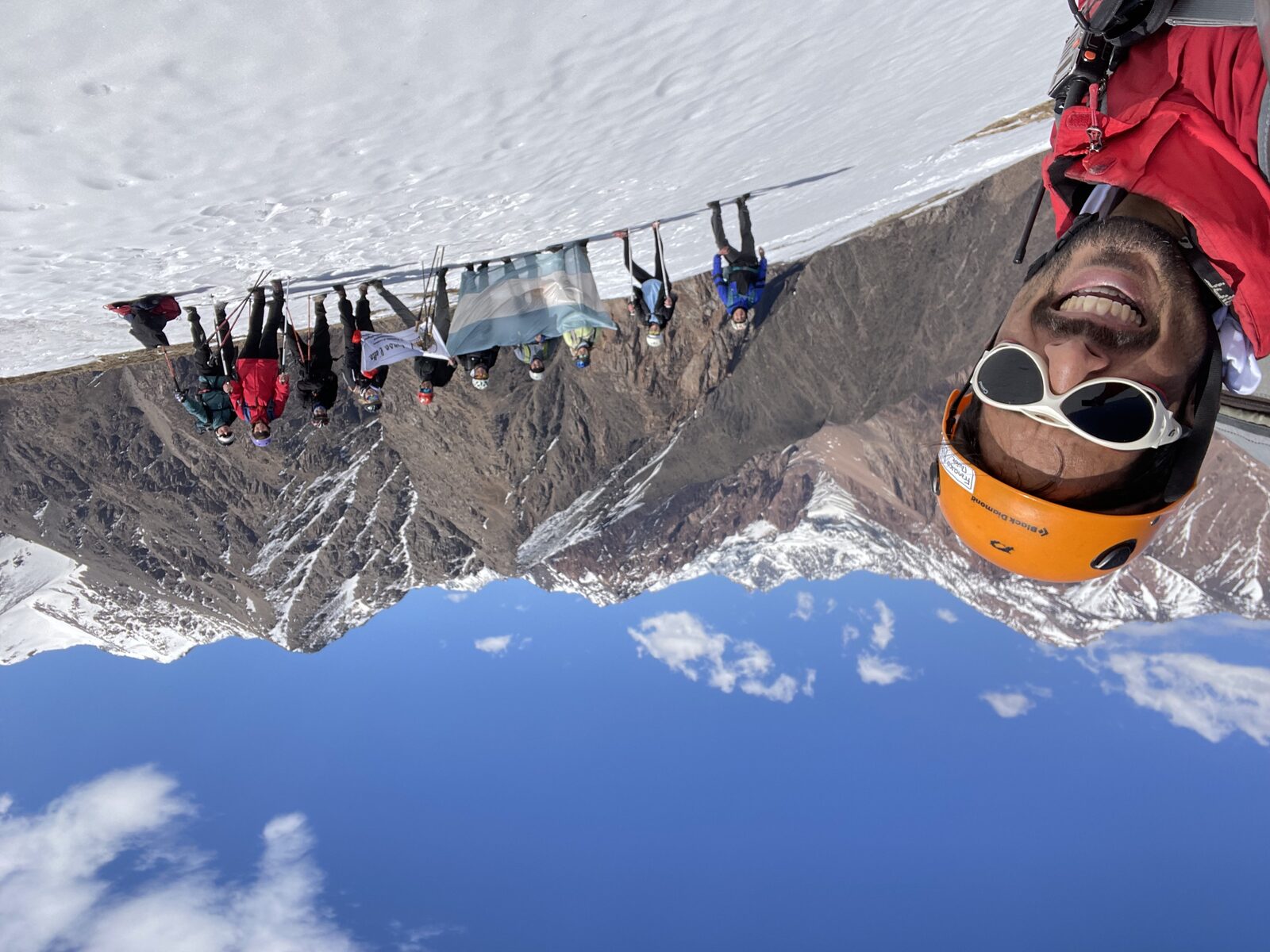 Francisco junto a un grupo en la cumbre de una montaña con bandera argentina