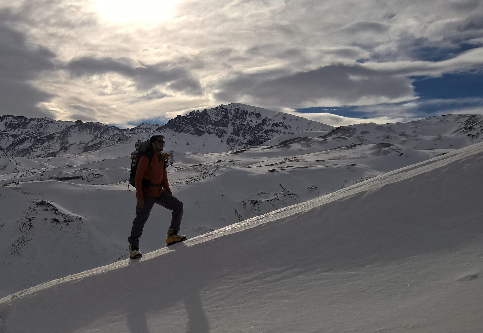 Francisco Muñoz caminando en la nieve con mochila de montaña, Andes argentinos