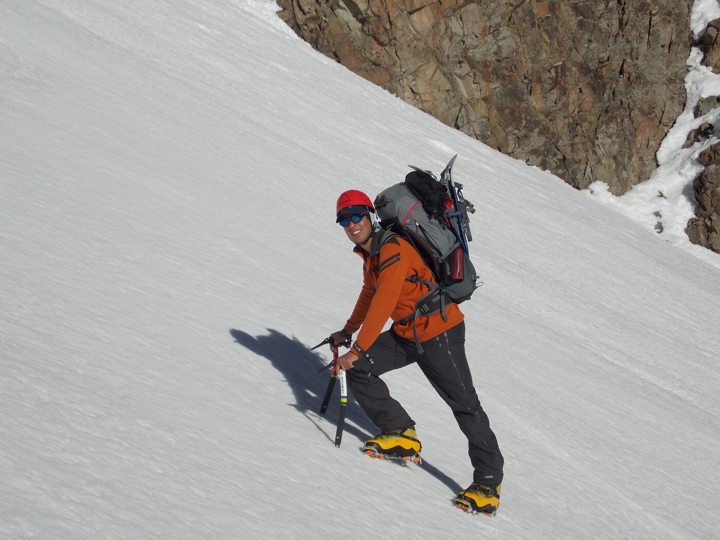 Francisco escalando con piolet y casco en una ladera nevada